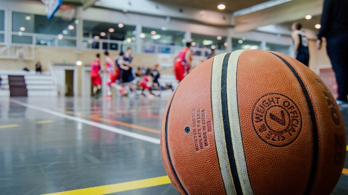 In einer Sporthalle liegt ein Basketball auf dem Boden.