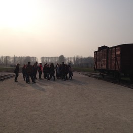 Eine Gruppe von Menschen steht links neben einem alten Zugwaggon.